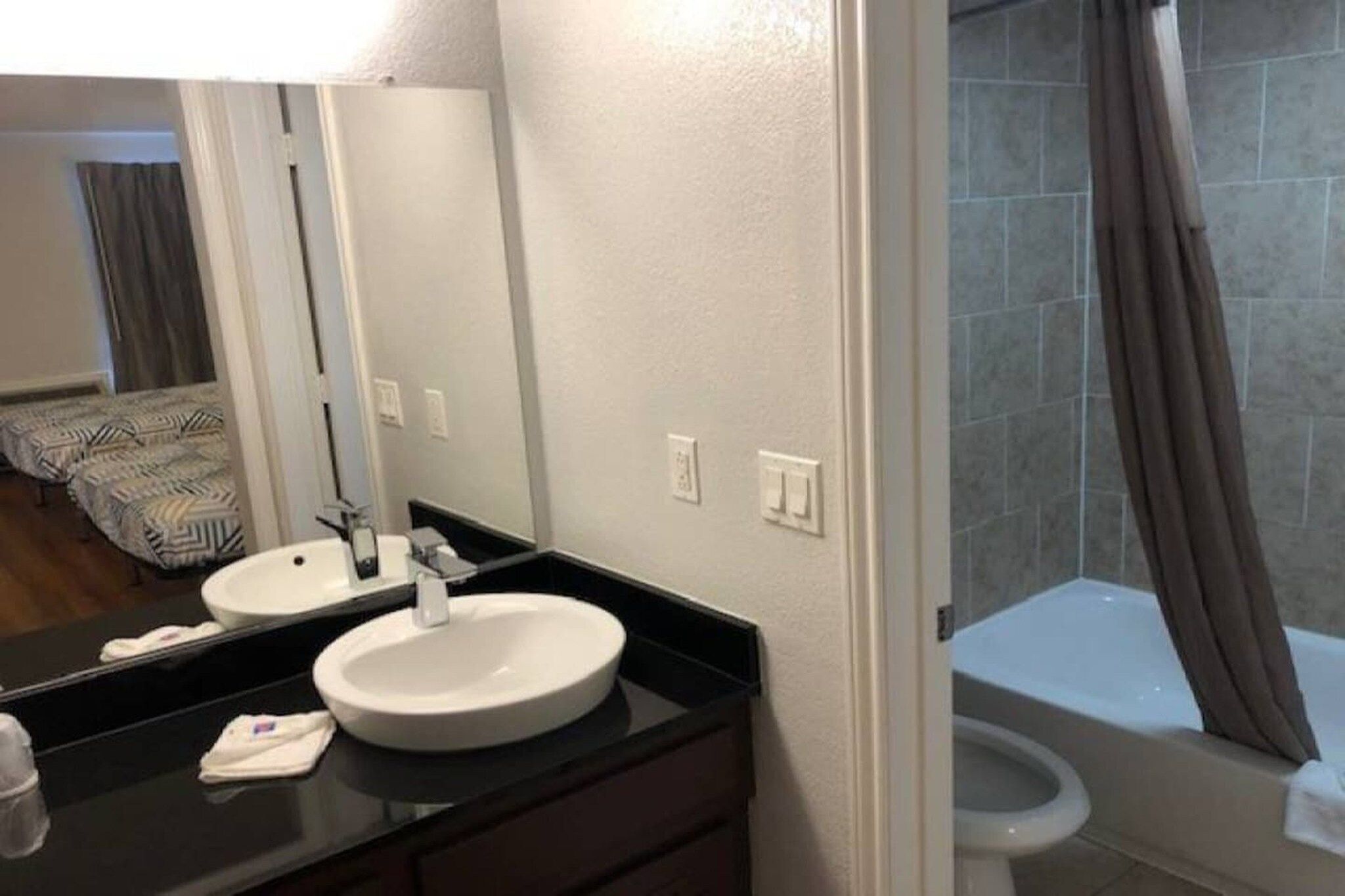 Un baño con lavamanos doble, espejo, inodoro y zona de ducha.
