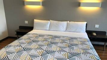 Una camera d'albergo con un letto, due comodini e illuminazione a parete.