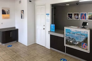 Un área de recepción con mostrador, una puerta y carteles informativos en la pared.