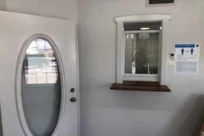 En dörr med en panel av frostat glas, ett litet fönster med en hylla och en säkerhetsanvisning på väggen.