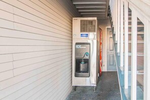 En ismaskin placerad utomhus vid en byggnad med ett tak av metall och en mur av tegelsten.
