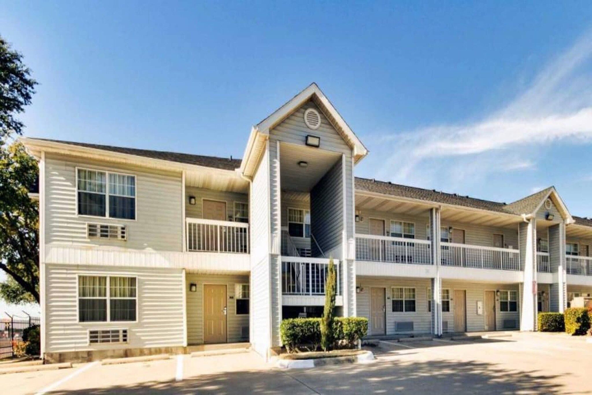 A multi-story motel with a central entrance, balconies, and a parking lot.
