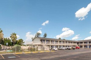 A motel with a parking lot, multiple floors, and a fenced area. - 1 King Bed | Smoking, Micfridge (Fort Worth)