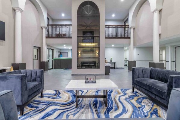 A spacious lobby with a marble-patterned rug, two sofas, a coffee table, and a central fireplace.