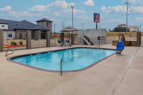 Una piscina con recinzione, sedie a sdraio e un cartello che indica una valutazione a 6 stelle.