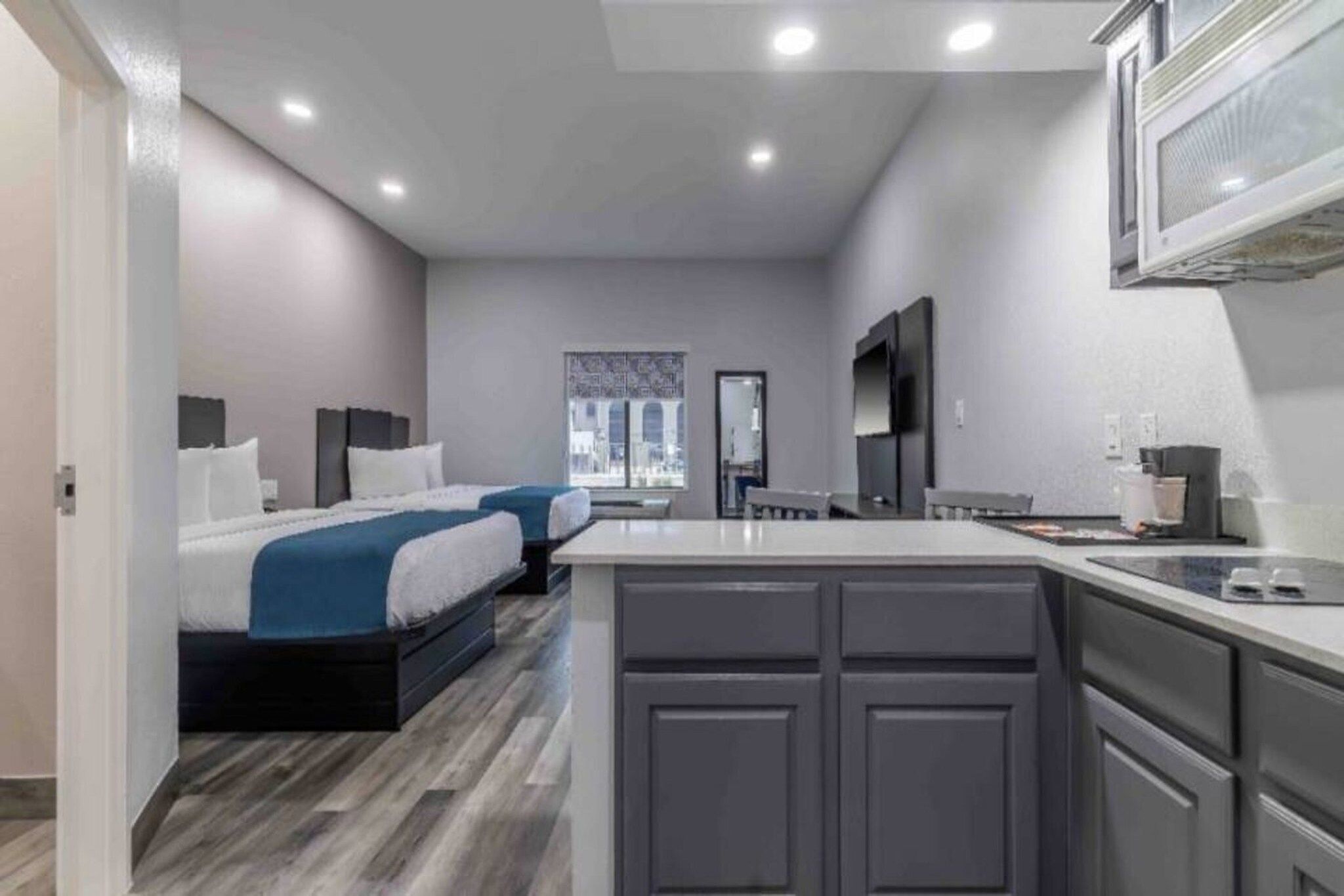 Habitación de hotel moderna con una cama grande, zona de estar separada, kitchenette y vista a la ciudad.