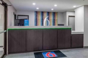 A reception area with a wooden reception desk, a colorful striped wall, and a blue logo on the floor.