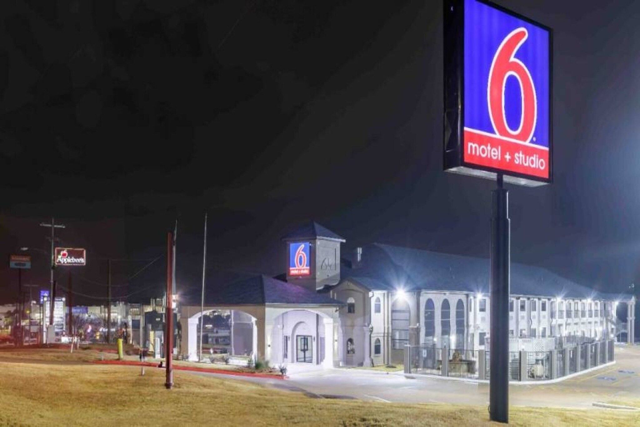 A motel with a prominent '6' sign, a covered parking area, and a building with multiple windows.