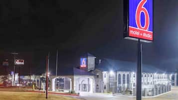 A motel with a prominent '6' sign, a covered parking area, and a building with multiple windows.