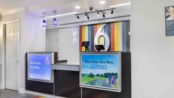 A reception desk with digital screens displaying promotional content.