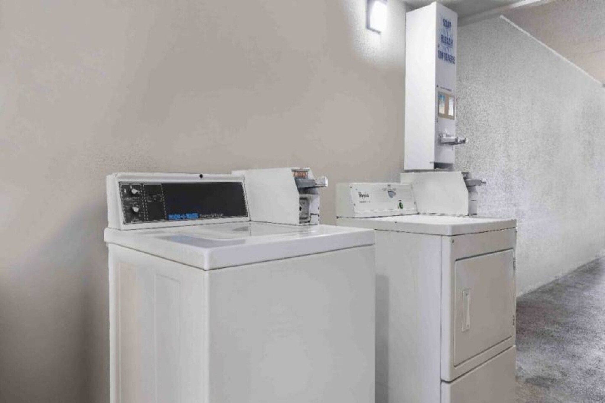 A laundry area with two white washing machines and a wall-mounted dryer.