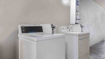 A laundry area with two white washing machines and a wall-mounted dryer.