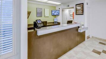 A reception area with a counter, a telephone, a television, and a welcome sign.