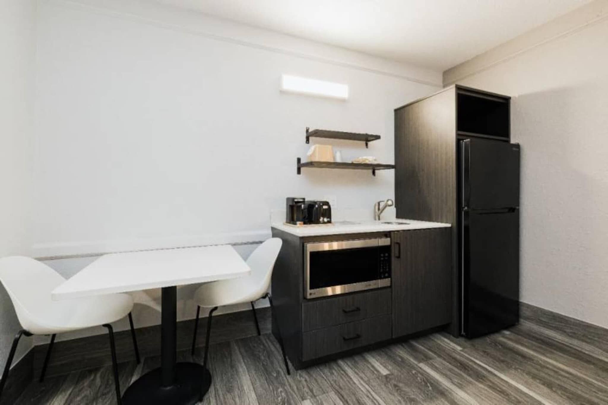 A compact kitchenette with a white countertop, a black refrigerator, and a built-in oven.