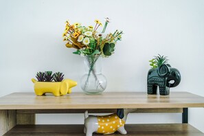 A wooden table with a clear glass vase containing flowers, a yellow planter with succulents, and a black elephant-shaped container. - Bright and Roomy 4BDR Home in Manchester (Manchester)