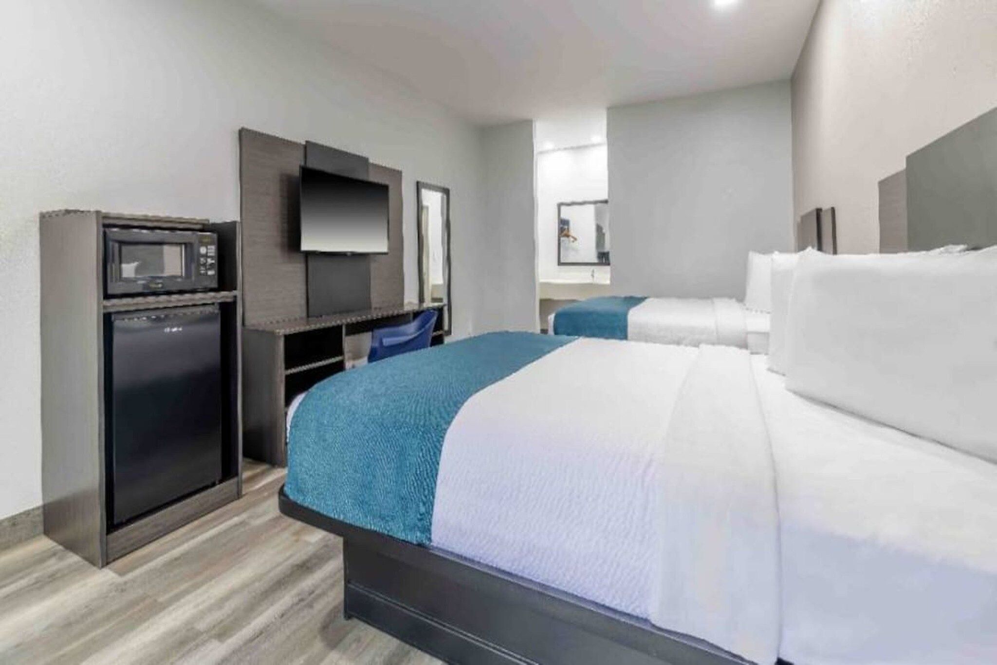 Une chambre d’hôtel avec un lit, un bureau avec un ordinateur et une télévision.