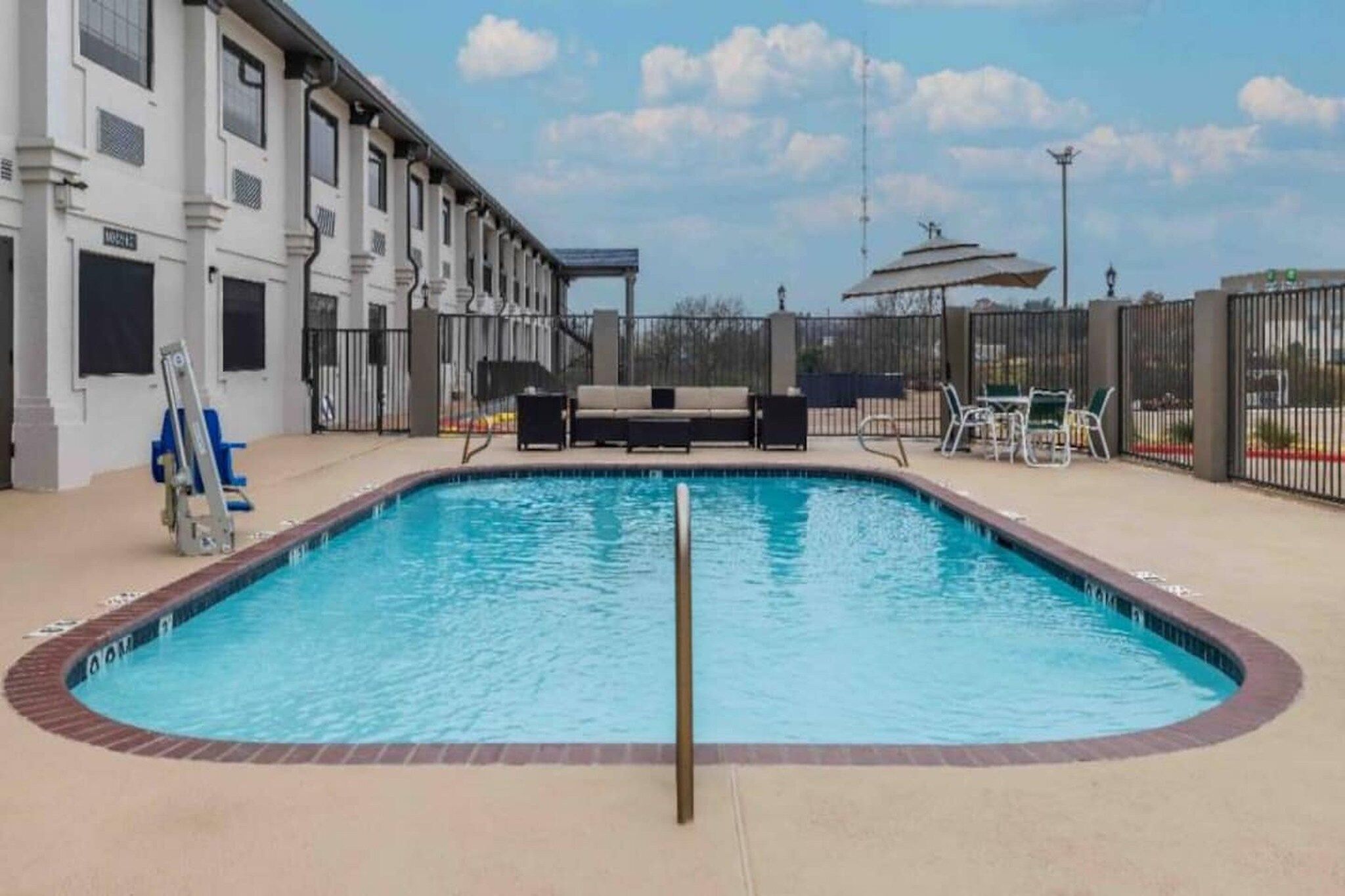 A swimming pool with a lifeguard stand, lounge chairs, and a covered seating area.