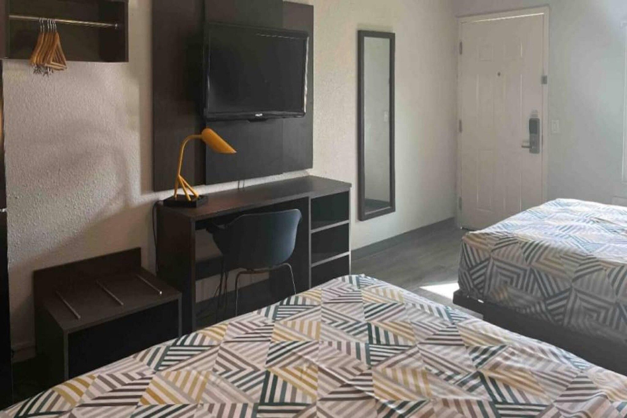 Une chambre d’hôtel comprenant un lit, un bureau, une chaise, une télévision et une armoire.