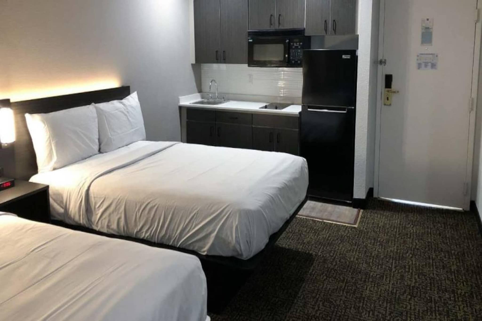 Une chambre d’hôtel avec deux lits, une kitchenette et un four à micro-ondes.
