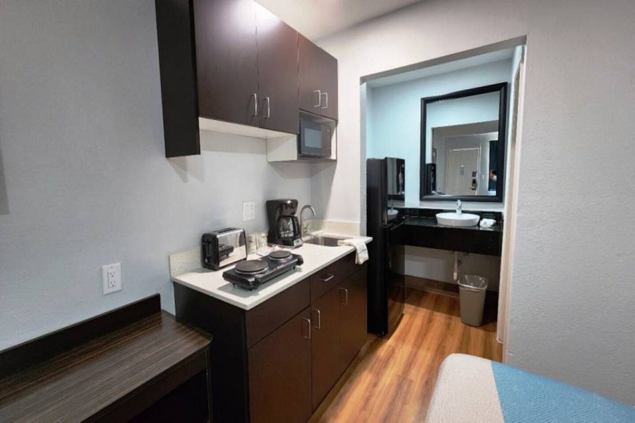 Een compacte kitchenette met een magnetron, koffiezetapparaat, broodrooster en een klein spoelbakje.