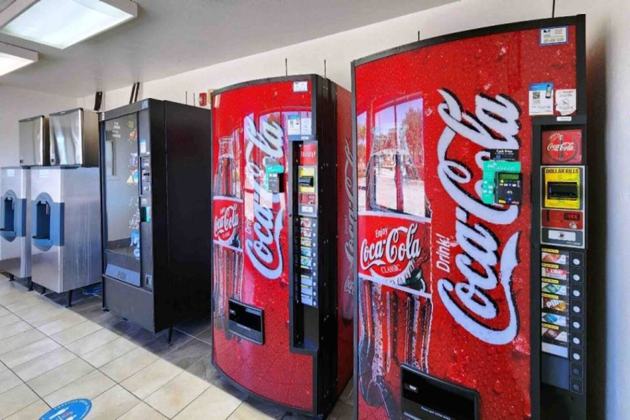 Een rij automaten, waaronder automaten met Coca-Cola branding, in een commerciële omgeving.