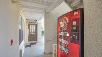 Un couloir avec un distributeur automatique de Dr Pepper rouge et une porte sur laquelle est inscrit « Laverie pour les clients ».