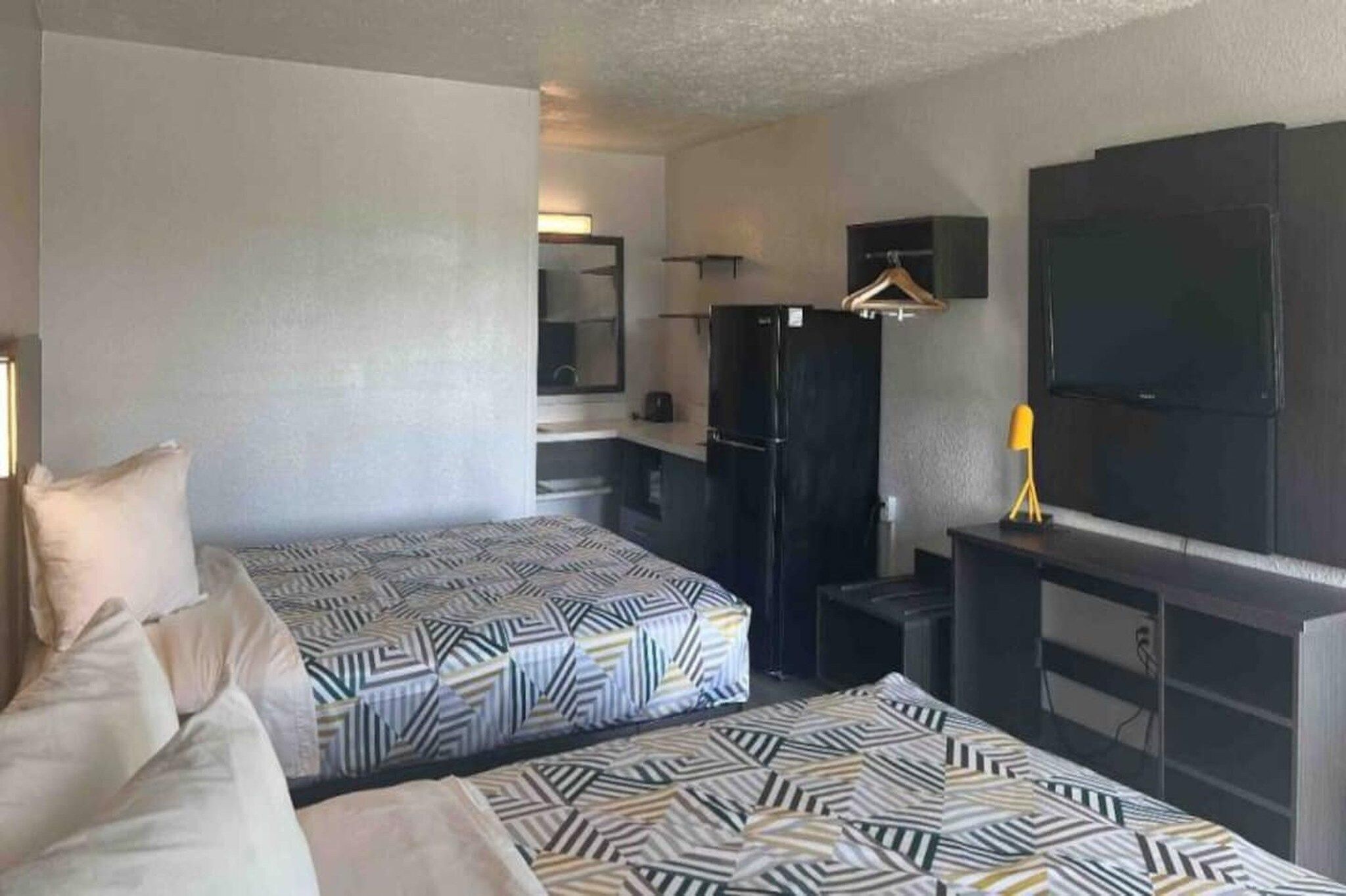 Une chambre d’hôtel avec deux lits, une télévision, un réfrigérateur et un petit bureau.