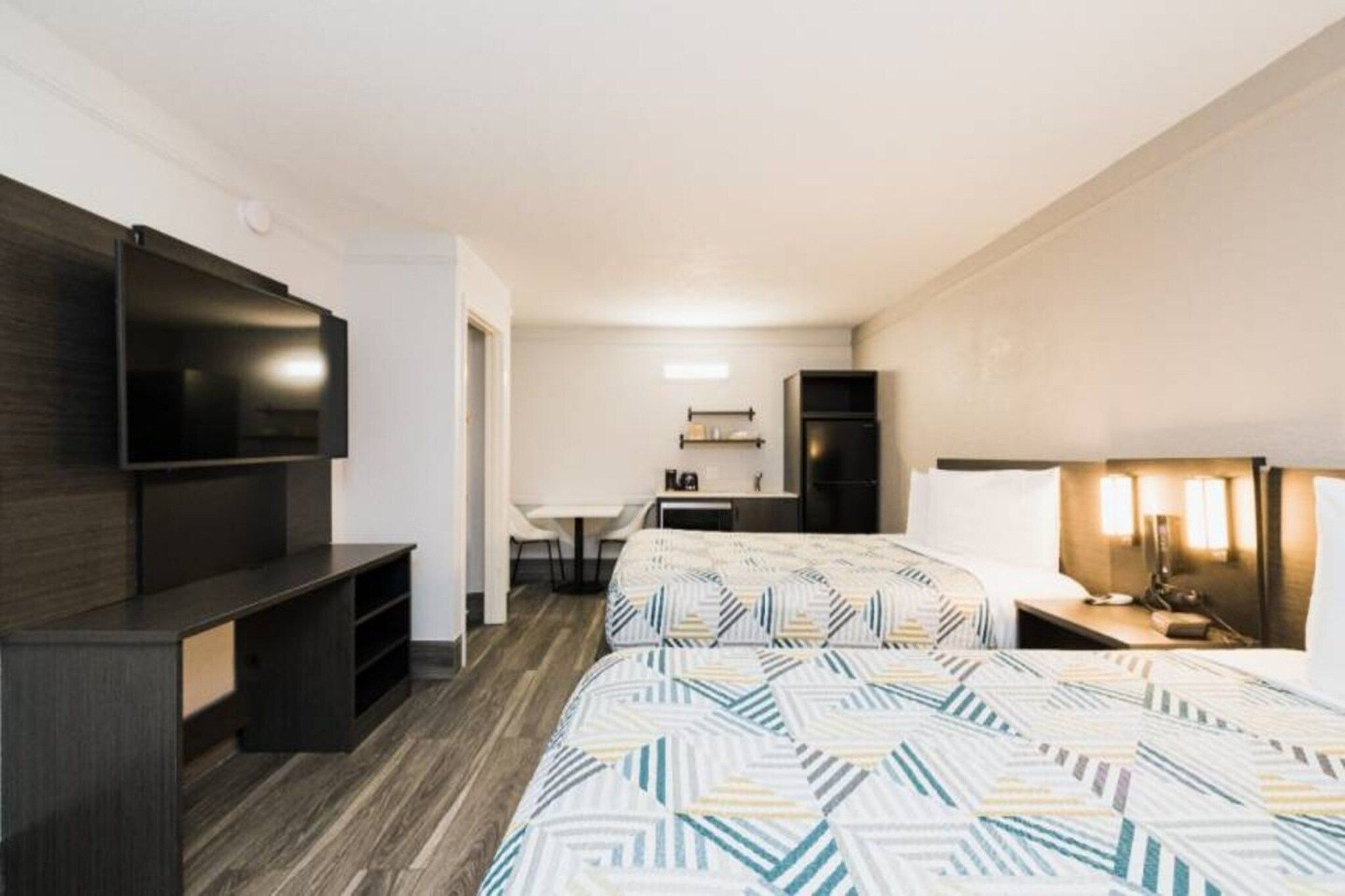A hotel room with two beds, a TV, a desk, and a chair.