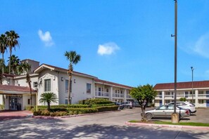 A motel with a central parking area, multiple-story buildings, and palm trees. - 1 King Bed | Kitchen, Smoking (Baytown)