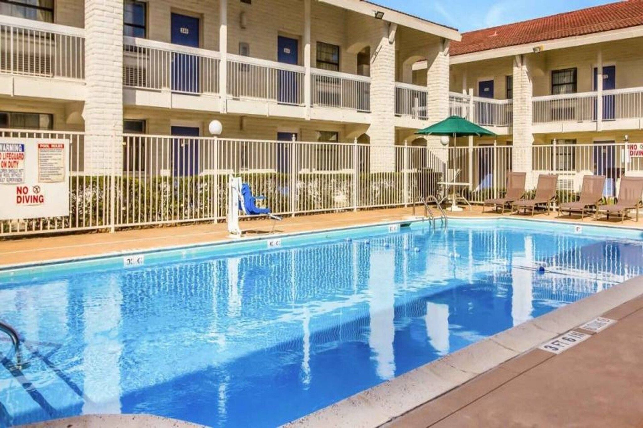 A swimming pool with a fenced area, lounge chairs, and a lifeguard stand.