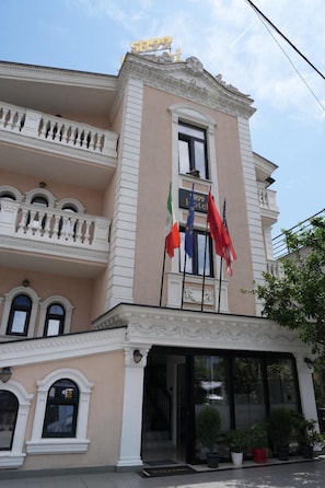 A hotel with a classic architectural style, featuring a balcony with ornate railings and a sign indicating the hotel's name. - Sr99 Hotel (Tirana)