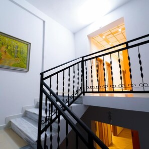A staircase with a black balustrade leading to a landing with a wooden door. - Sr99 Hotel (Tirana)
