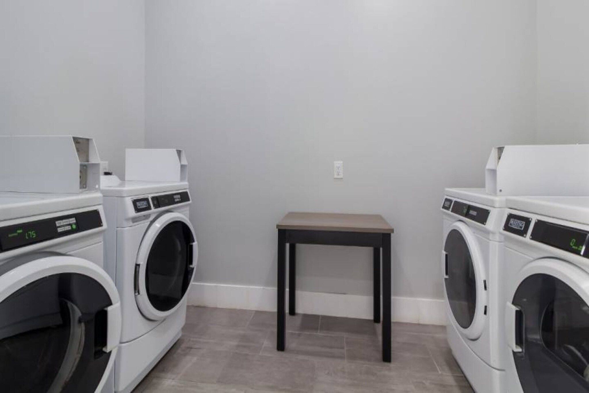 A laundry room with two front-loading washing machines and a small table.