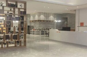 Un interior moderno con un mostrador de recepción, una estantería y una zona de estar.