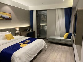 Una habitación de hotel con cama, sofá, escritorio y un panel de vidrio.