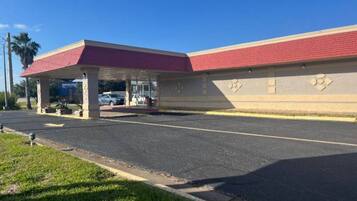 A building with a red roof and a covered parking area.