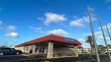 A building with a red roof and a blue sign indicating it is now open.