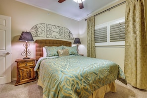A bedroom with a bed, two bedside tables, a headboard, a window with blinds, and a door. - Pool & River Access! Luxury Hill Country Haven (New Braunfels)