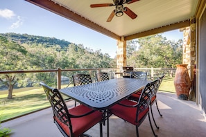 An outdoor patio with a table and chairs, a ceiling fan, and a view of a forested area. - Pool & River Access! Luxury Hill Country Haven (New Braunfels)