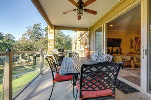 A covered patio with a table and chairs, a ceiling fan, and a view of the surrounding area. - Pool & River Access! Luxury Hill Country Haven (New Braunfels)