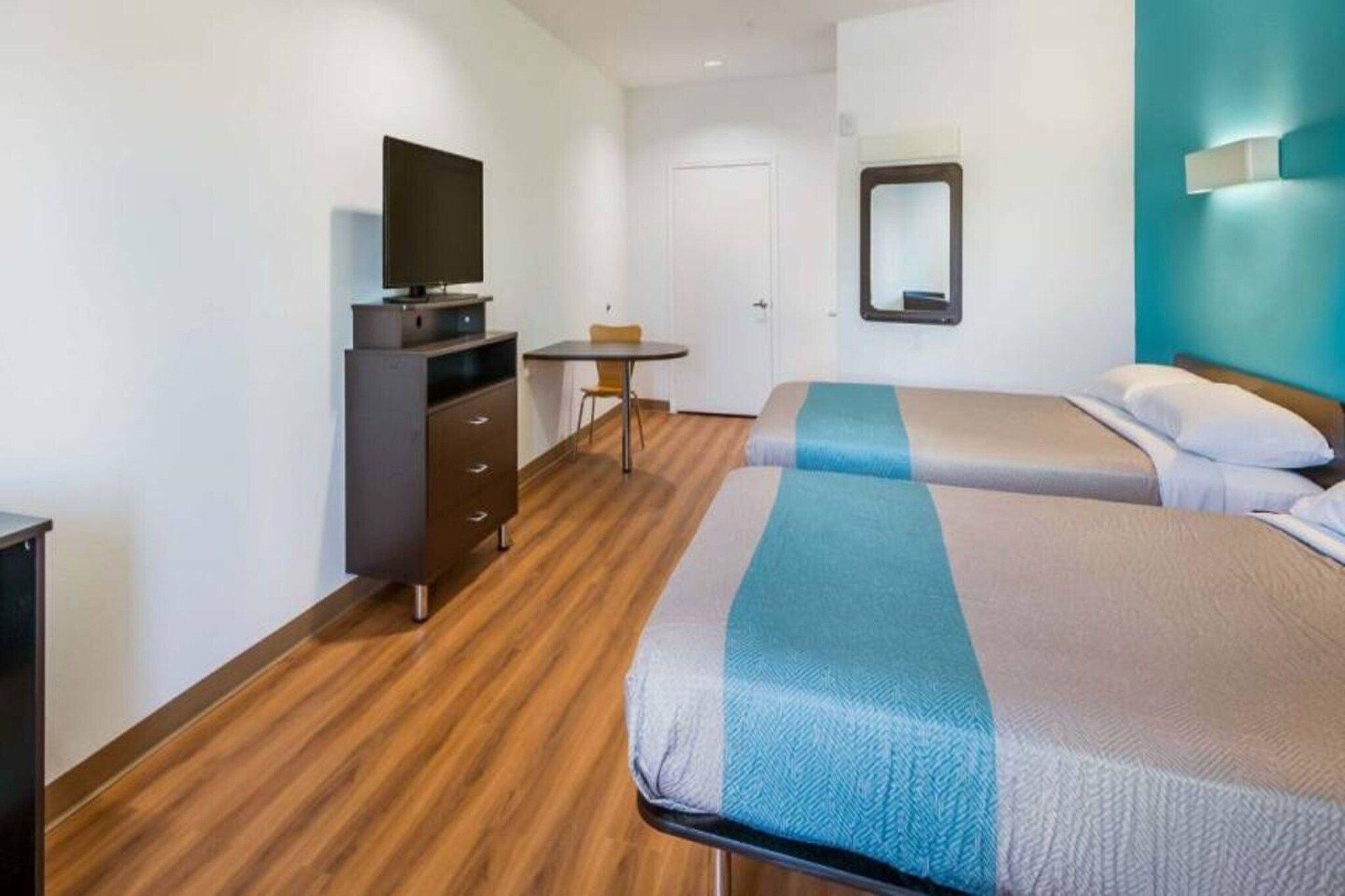 A hotel room with a bed, a desk, a chair, a television, and a wardrobe.