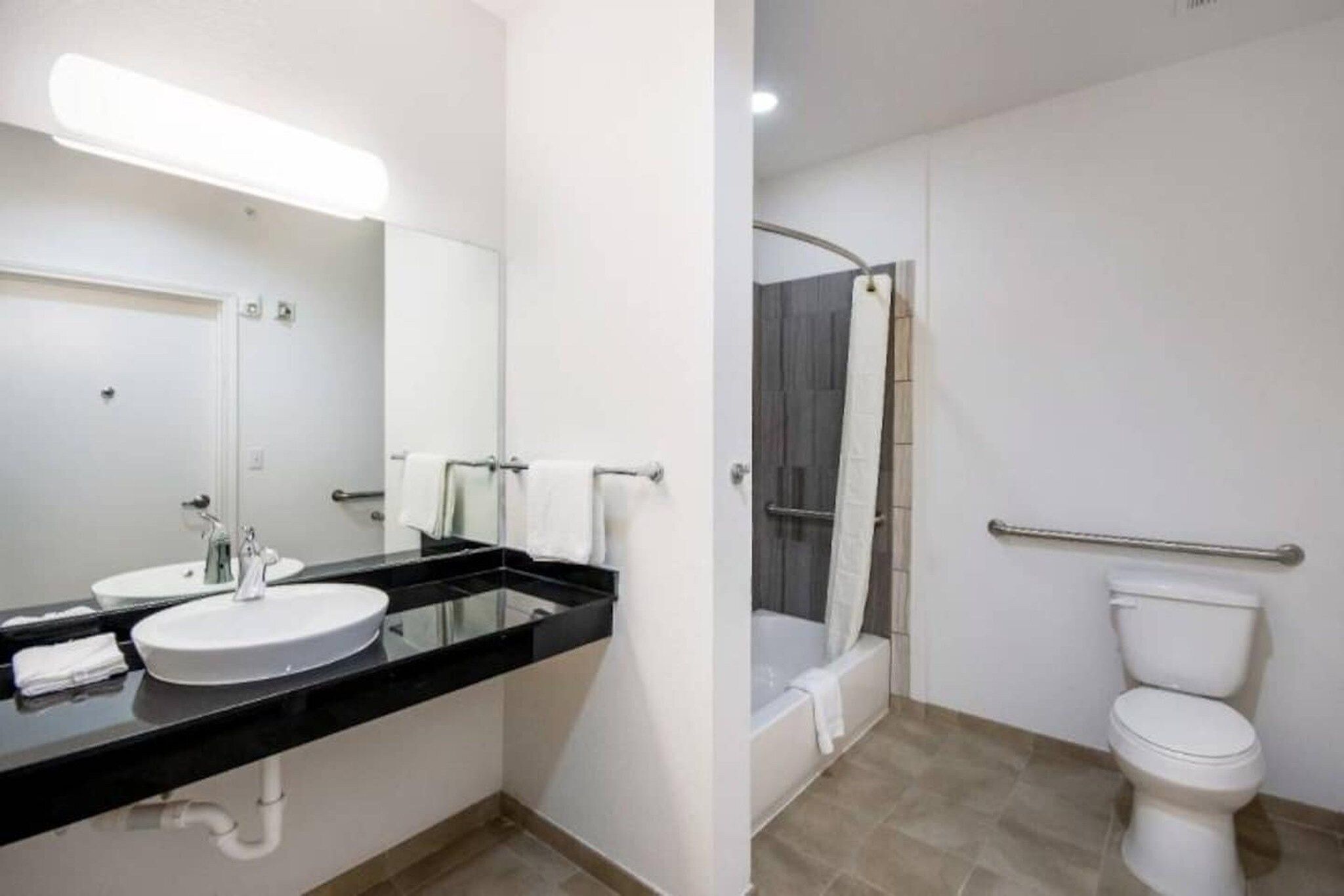 A modern bathroom with a black countertop, white sink, and a glass shower enclosure.