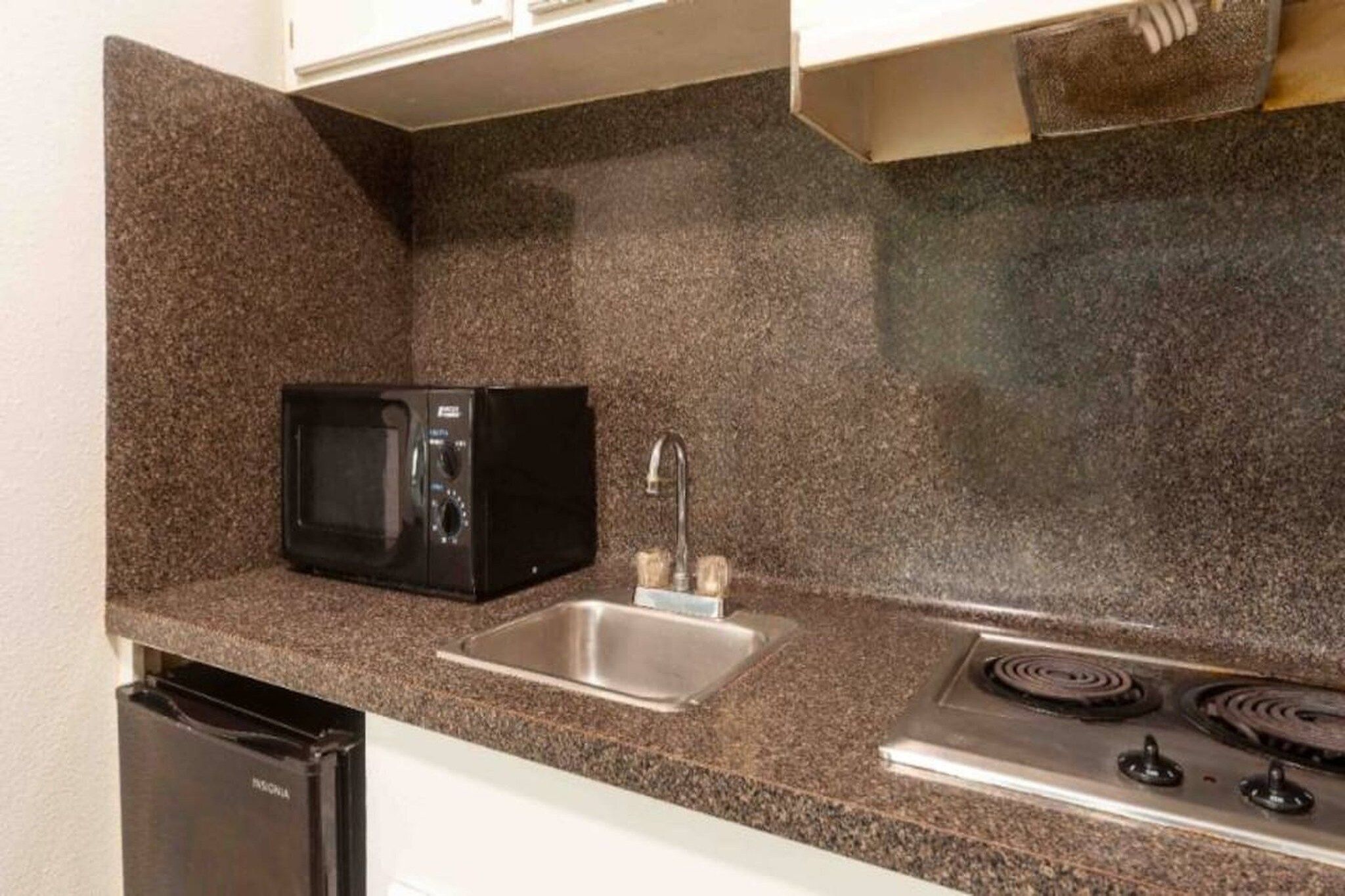 A compact kitchen with a microwave, sink, and stove.