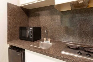 A compact kitchen with a microwave, sink, and stove.