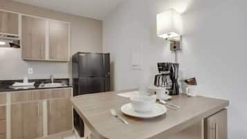 Una cocina moderna con refrigerador integrado, cafetera y comedor con mesa dispuesta para dos.