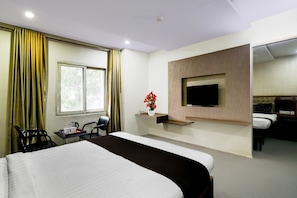 A hotel room with a large bed, a television mounted on the wall, a desk with a chair, and a window with curtains. - Townhouse Kothapet (Hyderabad)