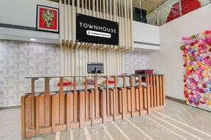 A reception desk with a sign indicating 'Company Serviced' and a framed picture of a deity above it. - Townhouse Kothapet (Hyderabad)