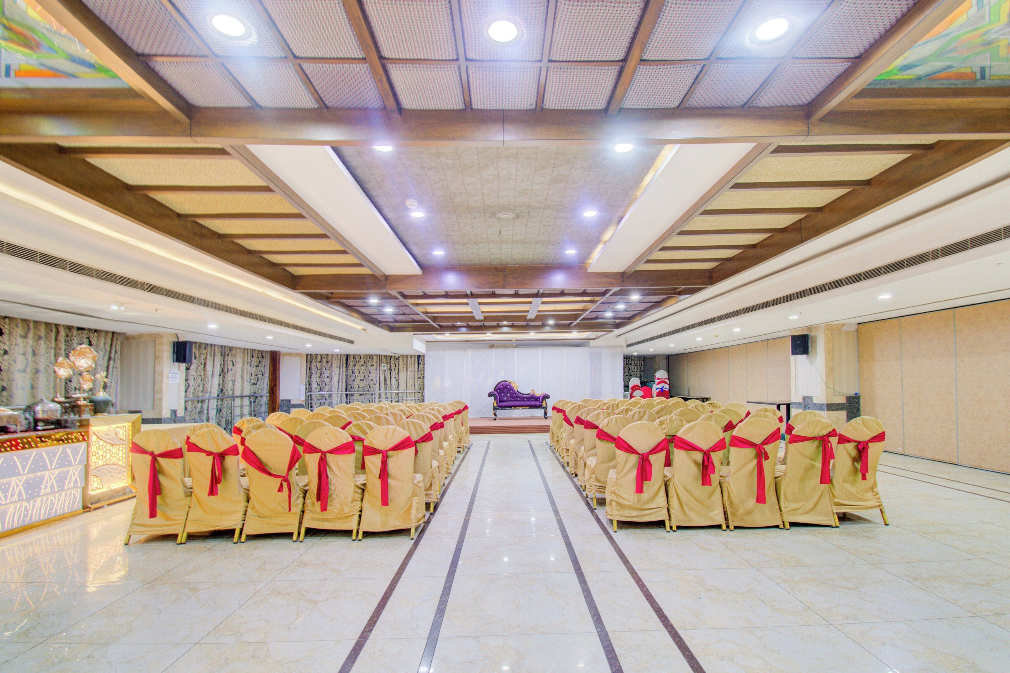 A banquet hall with rows of chairs, a stage, and a ceiling with recessed lighting.