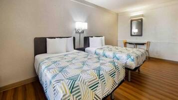 A hotel room with two beds, a small table, and a chair.