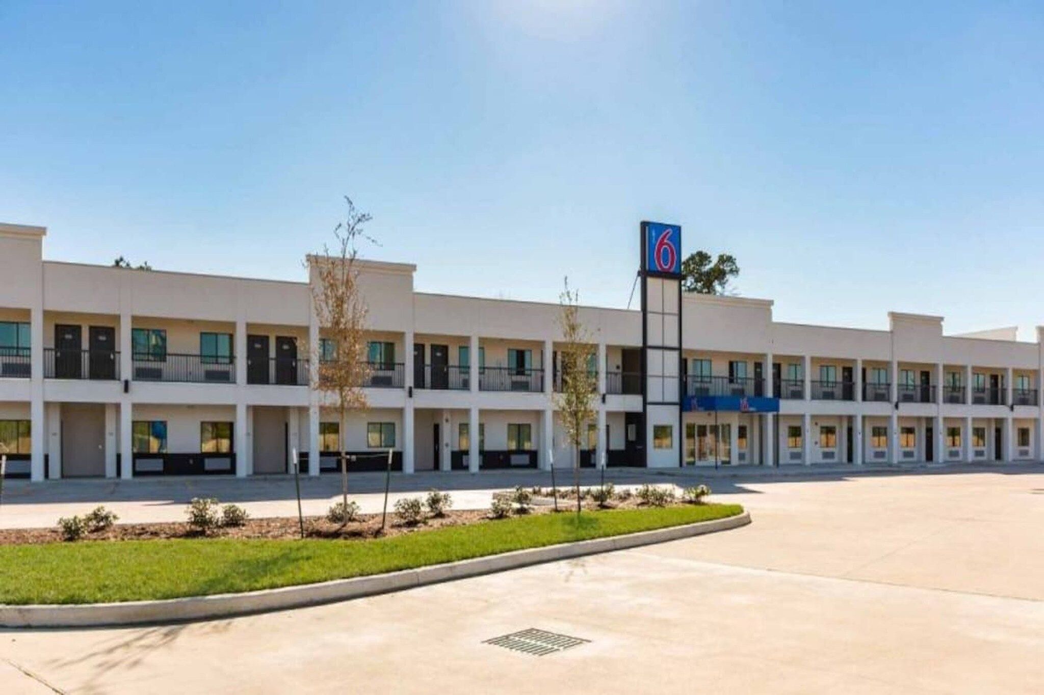 A multi-story hotel with a central courtyard, a sign indicating the number of rooms, and a clear sky.